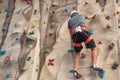 Young man practicing rock climbing on artificial wall indoors.