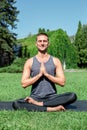 Healthy Lifestyle. Man practicing yoga outdoors sitting in lotus pose doing meditation smiling delightful Royalty Free Stock Photo