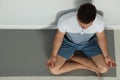 Young man practicing zen yoga near wall indoors, above view. Space for Royalty Free Stock Photo