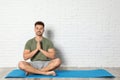 Young man practicing zen yoga near white brick wall, space for Royalty Free Stock Photo