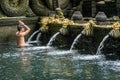 Young man praying in the holy spring water of Pura Tirta Empul  temple in Tampa, Bali, Indonesia Royalty Free Stock Photo