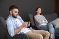 Young man preferring smartphone over his girlfriend at home. Relationship problems