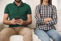 Young man preferring smartphone over his girlfriend at home. Relationship problems