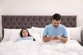 Young man preferring smartphone over his girlfriend at home