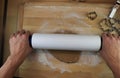 Young man prepare christmas paste for gingerbread cookies and take into forms as bell, car and others. Rolling dough with flour