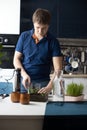 Young man preparing green wheatgrass juice using blender. Healthy antioxidant drink. Vertical