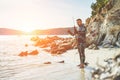 Young man preparing speargun for underwater fishing at sunset in italy - Male hunter getting ready for hunting wearing camouflage