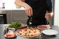 Young man preparing tasty pizza at table