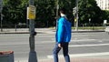 The young man presses the button, waiting until the green light and begins to cross the road. A man with a disability, limping