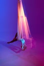 Young man, professional aerial gymnast, acrobat training on aerial fabric against gradient blue purple studio background