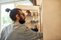 Young man, professional cook in apron taking ingredients out of the fridge while getting ready to prepare a meal Royalty Free Stock Photo