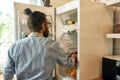 Young man, professional cook in apron taking ingredients out of the fridge while getting ready to prepare a meal Royalty Free Stock Photo