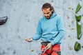 Young man professional rock climber checking sports equipment before climbing at training center in sunny day, outdoors Royalty Free Stock Photo