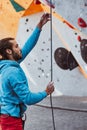 Young man professional rock climber checking sports equipment before climbing at training center in sunny day, outdoors Royalty Free Stock Photo