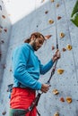 Young man professional rock climber checking sports equipment before climbing at training center in sunny day, outdoors Royalty Free Stock Photo