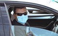 A young man in a protective mask and black goggles sits behind the wheel, right-hand drive, got into a traffic jam, the glass is Royalty Free Stock Photo