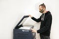 Young man in a protective mask makes copies of documents on a copy machine Royalty Free Stock Photo