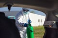 Man in protective suit with mask disinfecting inside car.