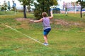 A young man in a public park learning to walk a tightrope