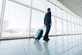 Young business man pulling suitcase in modern airport terminal. Travelling guy or businessman concept. Business trip Royalty Free Stock Photo
