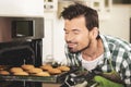 The young man pulls the cookies from the oven Royalty Free Stock Photo