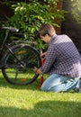 Young man pumping up bicycle tyre at park Royalty Free Stock Photo