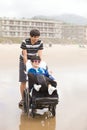 Young man pushing disabled little boy in wheelchair on beach Royalty Free Stock Photo