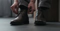 Young man put on his brown leather chukka boots indoor