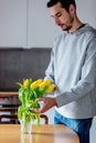 Young man put in yellow tulips in glass