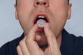 Young man puts in his mouth a sucking pill for sore throat. Self-medication for flu and cold. Sick with a sore throat, mint for fr