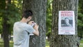 A young man puts up ads for a missing person in the park