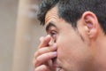 Young man putting contact lens in his eye Royalty Free Stock Photo