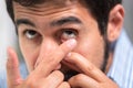 Young man putting contact lens in his left eye, close up. Royalty Free Stock Photo