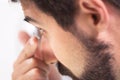 Young man putting contact lens in his left eye, close up. Royalty Free Stock Photo