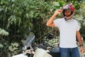 Young man putting on his helmet before taking a motorcycle ride in the countryside