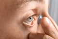 Young man putting lens in his eye, closeup Royalty Free Stock Photo