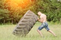 Young man raises tire. Workout