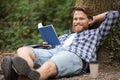 young man read book leaning against tree relaxing Royalty Free Stock Photo