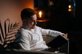 Young man read book sitting on armchair in dark living room. Royalty Free Stock Photo