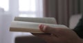 Young man read book while sitting on a sofa at home. Close up at book in hands. Royalty Free Stock Photo