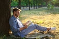 Young man reading book on green grass near tree in park Royalty Free Stock Photo