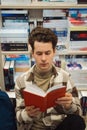 Young man reading book intently in library surrounded by literature Royalty Free Stock Photo