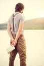 Young Man reading book outdoor with scandinavian lake on background