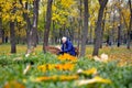 young man reading a book outdoors sitting on a bench in autumn park Royalty Free Stock Photo