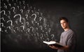 Young man reading a book with question marks coming out from it Royalty Free Stock Photo