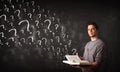 Young man reading a book with question marks coming out from it Royalty Free Stock Photo