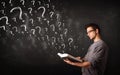 Young man reading a book with question marks coming out from it Royalty Free Stock Photo