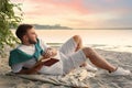 Young man reading book on sandy beach near sea Royalty Free Stock Photo