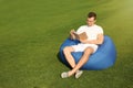 Young man reading book while sitting on bean bag chair outdoors Royalty Free Stock Photo