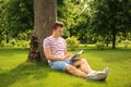 Young man reading book while sitting near tree in park Royalty Free Stock Photo